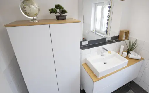 Weißer Badschrank mit Abdeckung in Eiche neben passendem Waschtisch mit Aufsatzbecken