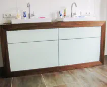 Doppelwaschtisch mit hellen Glasfronten in einem Rahmen aus dunklem Holz und zwei flachen Aufsatzbecken
