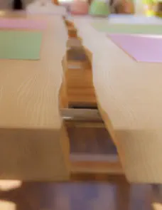 Detail eines Baumkantentischs aus zwei massiven Holzplatten, deren Baumkanten sich in der Tischmitte gegenüberliegen