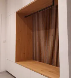 Weiße Einbaugarderobe nach Maß mit offener Eichennische, Lamellenrückwand und schwarzer Kleiderstange