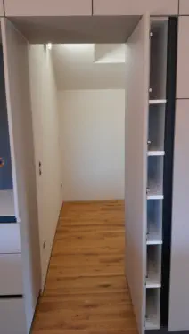 Weißer Einbauschrank als Durchgang mit schmalem, offenem Seitenregal und Eichenboden
