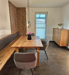 Essbereich mit Eckbank vor Holzlamellenwand, Esstisch in Eiche und Sideboard mit Lamellenfront