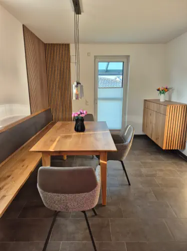Essbereich mit Eckbank vor Holzlamellenwand, Esstisch in Eiche und Sideboard mit Lamellenfront