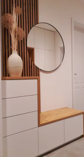Flurgarderobe mit Holzlamellenwand, rundem Spiegel, weißen Schubladen und Sitzbank in Eiche
