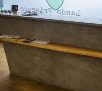 Empfangstheke in Betonoptik mit Ablage aus Holz in einem Friseursalon