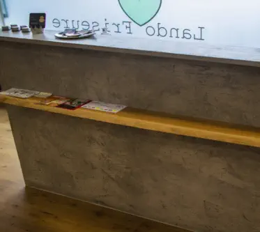 Empfangstheke in Betonoptik mit Ablage aus Holz in einem Friseursalon
