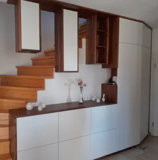Weißes Sideboard mit Holzabdeckung und offenen Regalen entlang einer Holztreppe