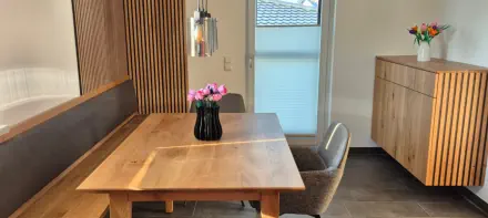 Essbereich nach Maß mit Eckbank vor Holzlamellenwand, Esstisch in Eiche und Sideboard mit Lamellenfront