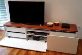 Weißes TV-Lowboard mit Holzabdeckung, Schubladen und offener Klappe für Receiver und Mediengeräte